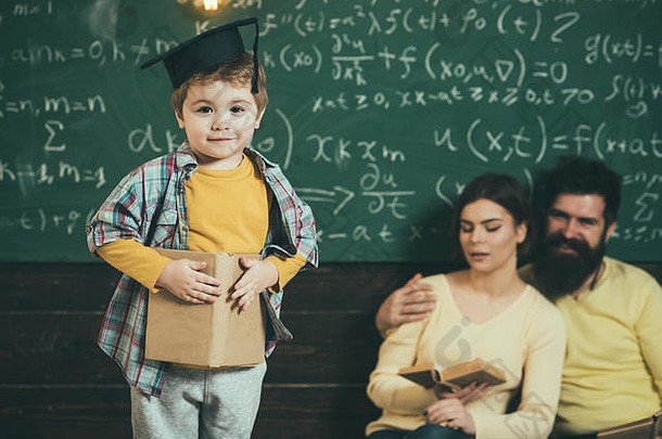 父母听儿子检查错误书黑板背景男孩展示知识妈妈爸爸聪明的孩子