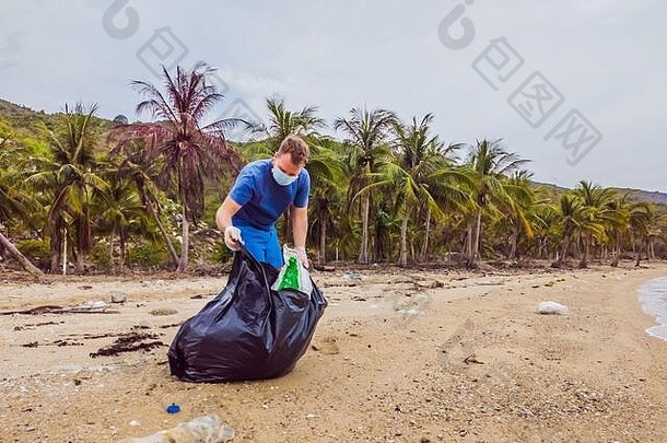 男人。手套选择塑料袋污染海问题泄漏垃圾垃圾垃圾海滩沙子引起的人为造成的污染运动