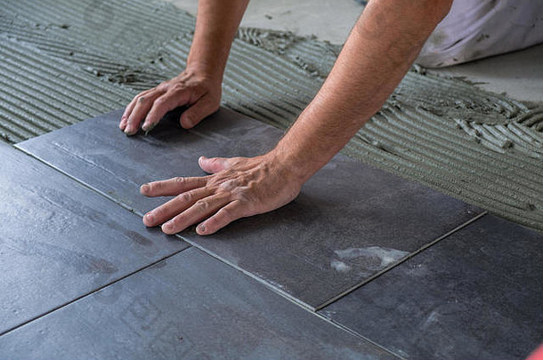 工人放置陶瓷地板上瓷砖胶粘剂表面