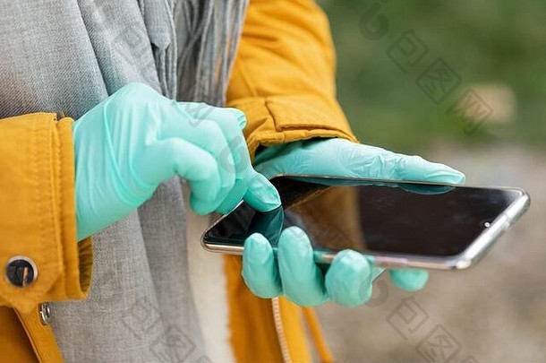 关闭图片女手保护手套持有电话卫生保护新冠病毒