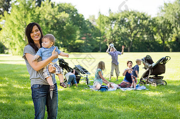 快乐妈妈。携带婴儿男孩公园