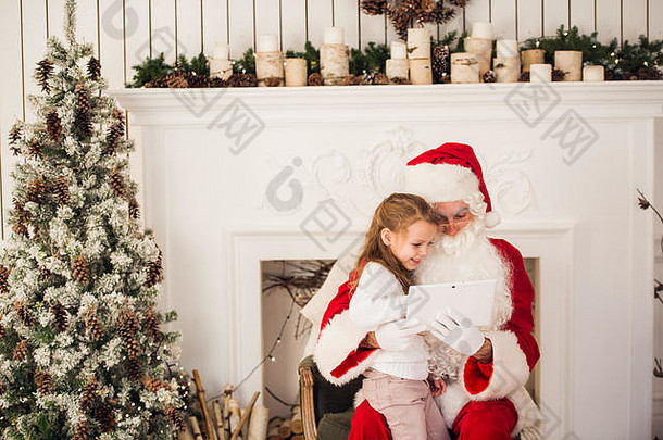 圣诞节假期快乐女孩圣诞老人数字触摸屏幕平板电脑烟囱树色彩斑斓的灯背景