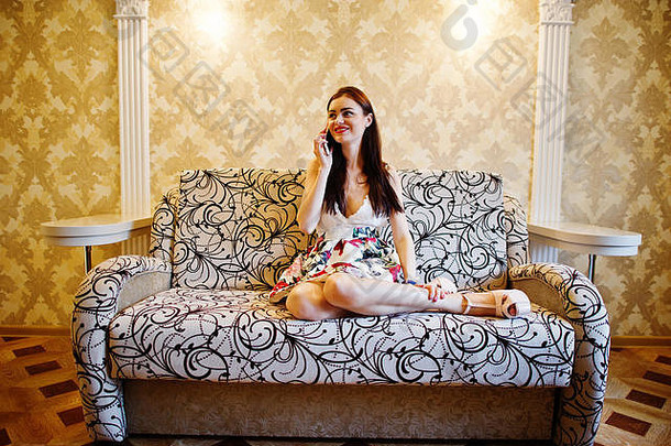 肖像有吸引力的年轻的女人会说话的电话坐着沙发
