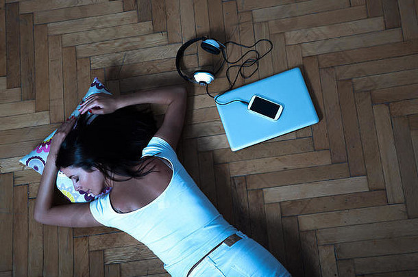 年轻的美丽的女人铺设地板上移动PC智能手机咖啡耳机