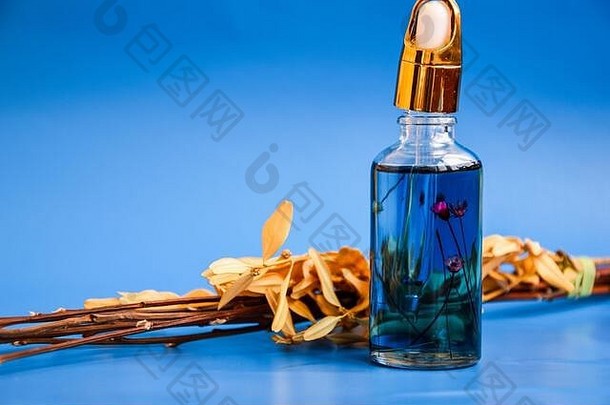 反老化血清玻璃瓶下降蓝色的背景干花面部液体血清胶原蛋白肽角质层石油