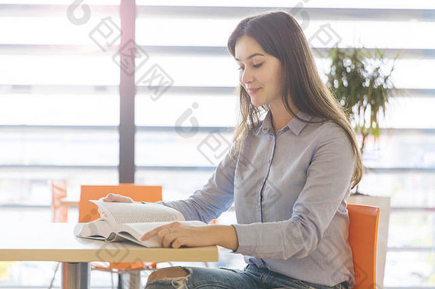 肖像年轻的美丽的女人坐着咖啡馆阅读书