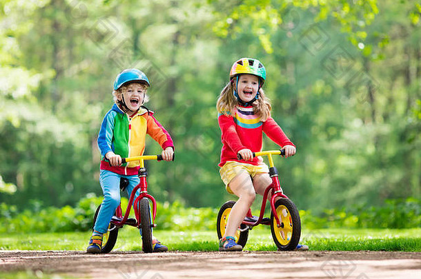 孩子们骑平衡自行车孩子们自行车阳光明媚的公园女孩男孩骑滑翔机自行车温暖的夏天一天学龄前儿童学习平衡