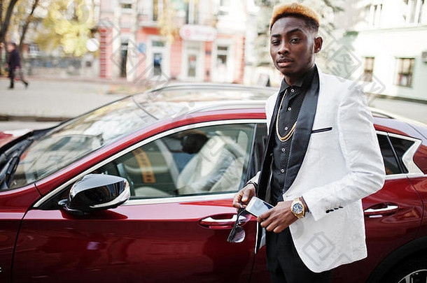 别致的英俊的非洲美国男人。白色西装红色的奢侈品车移动电话手