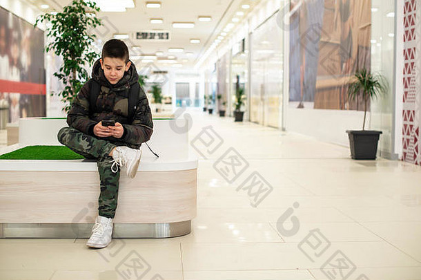 少年玩智能手机现代商业中心板凳上花能现代建筑室内技术沟通凹陷