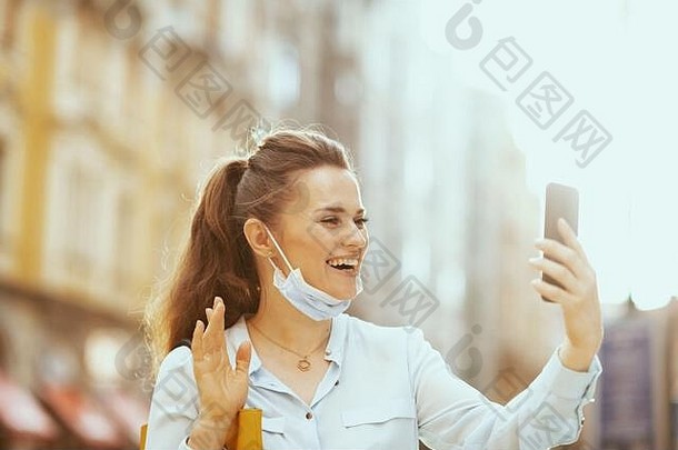 生活冠状病毒流感大流行快乐时尚的女蓝色的上衣医疗面具手提包视频会议在户外城市斯特里