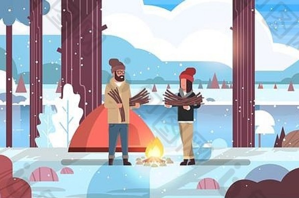 夫妇游客徒步旅行者持有柴火男人。女人组织火营帐篷徒步旅行野营概念冬天景观自然河山
