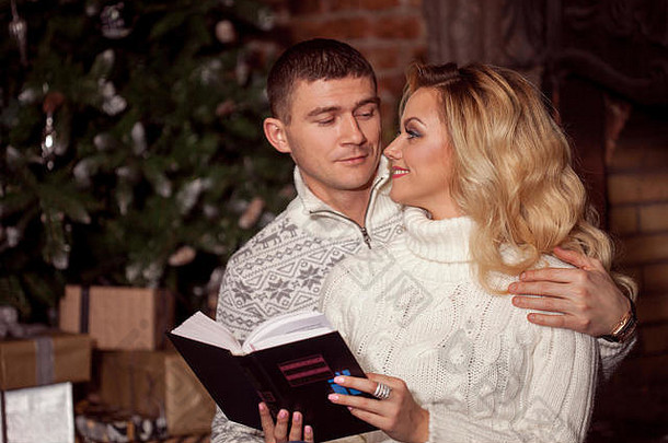 年轻的夫妇<strong>阅读</strong>书圣诞节树背景