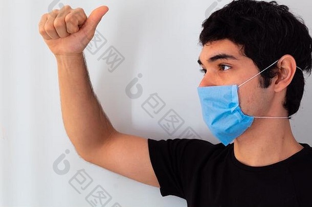 年轻的男人。穿蓝色的医疗面具白色背景显示人问候避免科维德感染