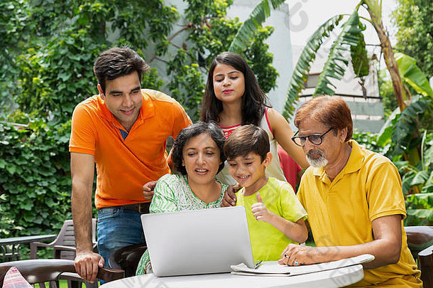 快乐multi-generation家庭院子里视频闲谈，聊天移动PC在花园首页