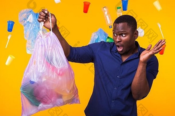 问题垃圾塑料回收污染环境概念惊讶男人。携带垃圾袋黄色的背景