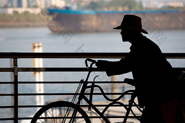 中国人男人。推自行车河船背景
