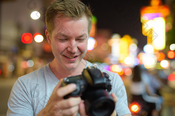 脸年轻的快乐旅游男人。检查相机街道唐人街晚上
