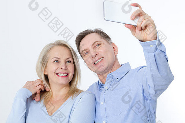 快乐中间岁的夫妇采取自拍智能手机孤立的白色