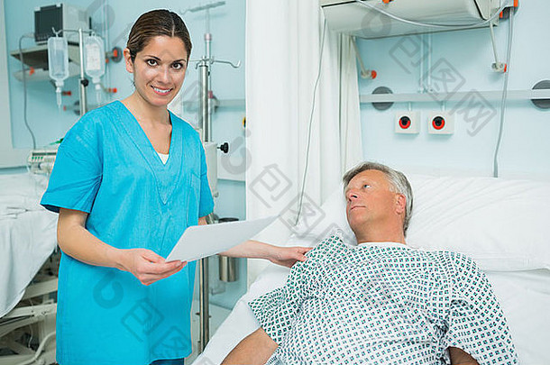 微笑护士触碰肩膀病人说谎床上持有纸
