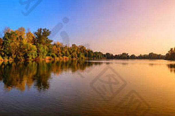 全景华丽的日落湖黄金蓝色的颜色树反映了水