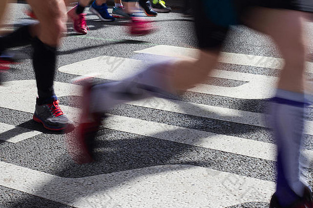 特写镜头一边视图马拉松跑步者脚腿运动模糊运行光早....城市停机坪上路