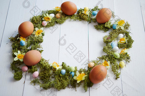 色彩斑斓的装饰复活节鸡蛋花环白色木表格背景