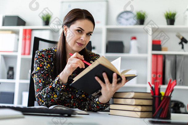 年轻的女孩坐着办公室电脑桌子上工作书