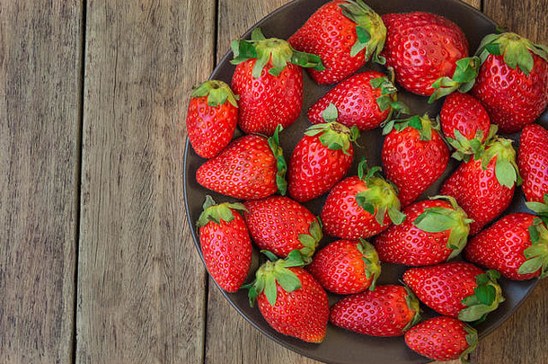 成熟的有机草莓黑暗板板材木背景关闭健康的食物排毒前视图