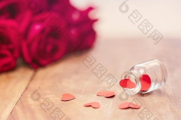 可爱的红色的心溢出小玻璃瓶木表格红色的玫瑰花束模糊背景复制空间