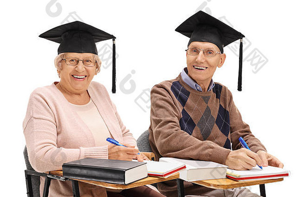 快乐的老年人毕业帽子坐着学校椅子相机孤立的白色背景