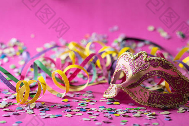 狂欢节聚会，派对粉红色的黄金面具飘带五彩纸屑明亮的粉红色的背景横幅