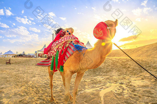 快乐女人说谎骆驼沙子沙丘海滩chorudaid波斯海湾南部卡塔尔高加索人旅游享受骆驼骑日落