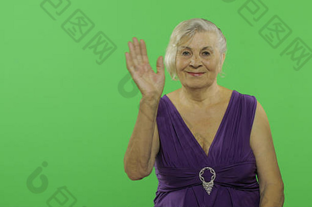 上了年纪的女人挥舞着相机微笑漂亮的祖母紫色的衣服的地方标志文本浓度关键绿色屏幕背景