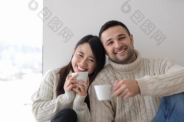 快乐年轻的多民族夫妇享受早....咖啡窗口冷冬天一天首页