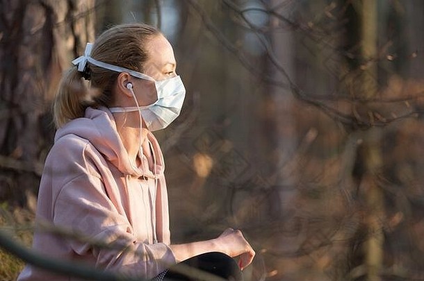 肖像高加索人运动女人穿医疗保护脸面具放松自然听音乐电晕病毒科维德