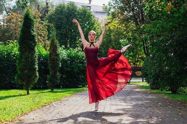 女人芭蕾舞女演员红色的芭蕾舞衣服跳舞尖端鞋子秋天公园