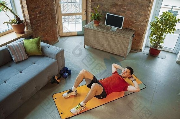 仰卧起坐年轻的高加索人男人。培训首页检疫冠状病毒爆发练习健身有氧记录视频流媒体在线健康体育运动运动概念