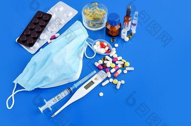 医疗保护面具药片温度计药物注射器蓝色的桌子上医疗保健医疗概念