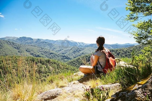 徒步旅行者女孩坐着岩石考虑景观山夏天