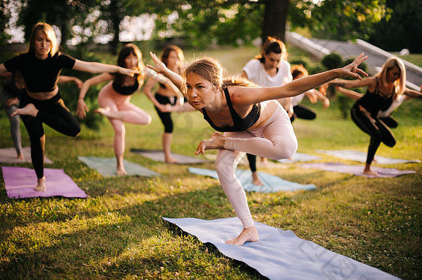 集团年轻的女人运动服装站瑜伽位置腿