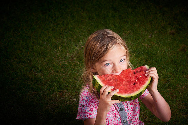 可爱的金发碧眼的女孩吃西瓜草夏季