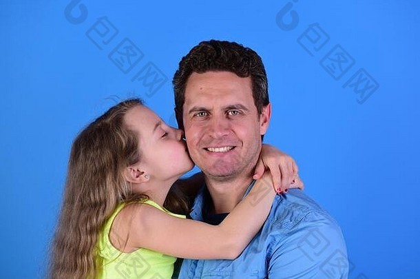童年家庭概念女孩男人。快乐脸蓝色的背景女儿父亲拥抱女学生吻爸爸脸颊