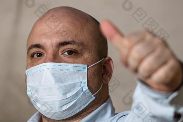 生病的年轻的男人。拇指穿保护面具电晕病毒科维德男人。穿外科手术面具防止病毒疾病新冠病毒