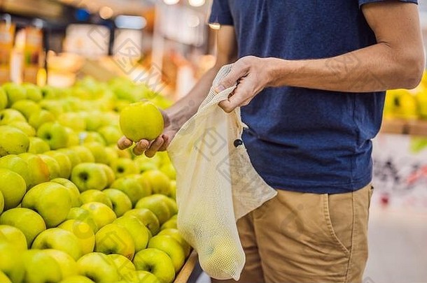 男人。选择<strong>苹果</strong>超市塑料袋可重用的袋购买蔬菜浪费概念