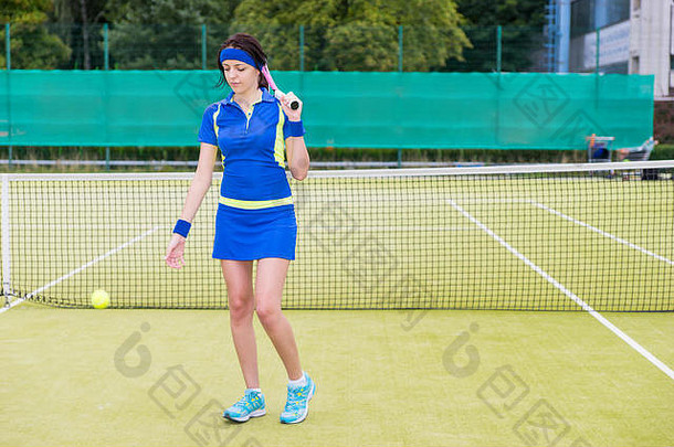 美丽的女网球球员穿运动服装持有球拍肩膀抛出球匹配网球