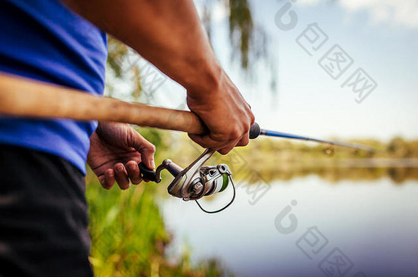 年轻的男人。钓鱼河日落特写镜头菲瑟曼持有杆钓鱼设备衣服旋转