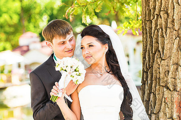 快乐微笑新婚夫妇有趣的接吻在户外婚礼一天