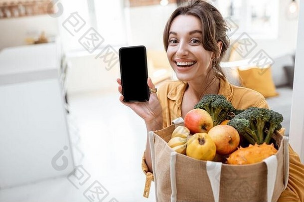 肖像年轻的快乐的女人持有聪明的电话购物袋完整的新鲜的水果蔬菜首页电话空屏幕复制粘贴