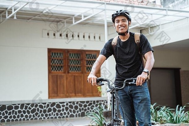微笑亚洲年轻的男人。站<strong>折叠自行车</strong>