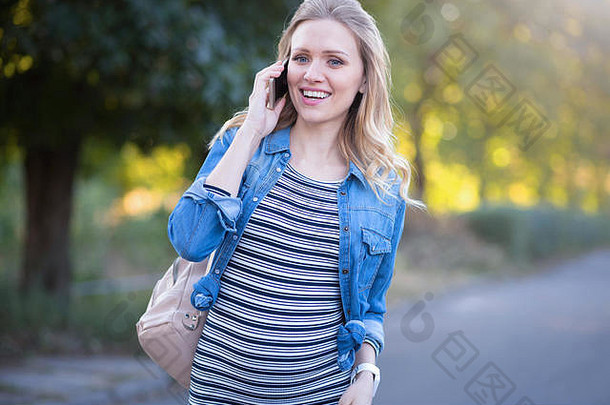 很高兴怀孕了女人享受谈话电话在户外